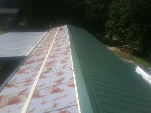 Old rusted panels beside newly installed green metal roofing — Wind Damage Roof Repair by Roofing Brothers in Cassville