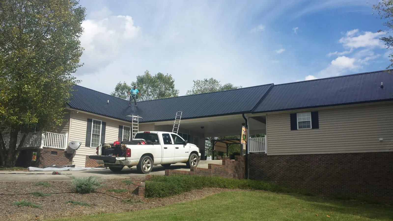 Black metal roof over a home and attached breezeway with ladders set in Cassville